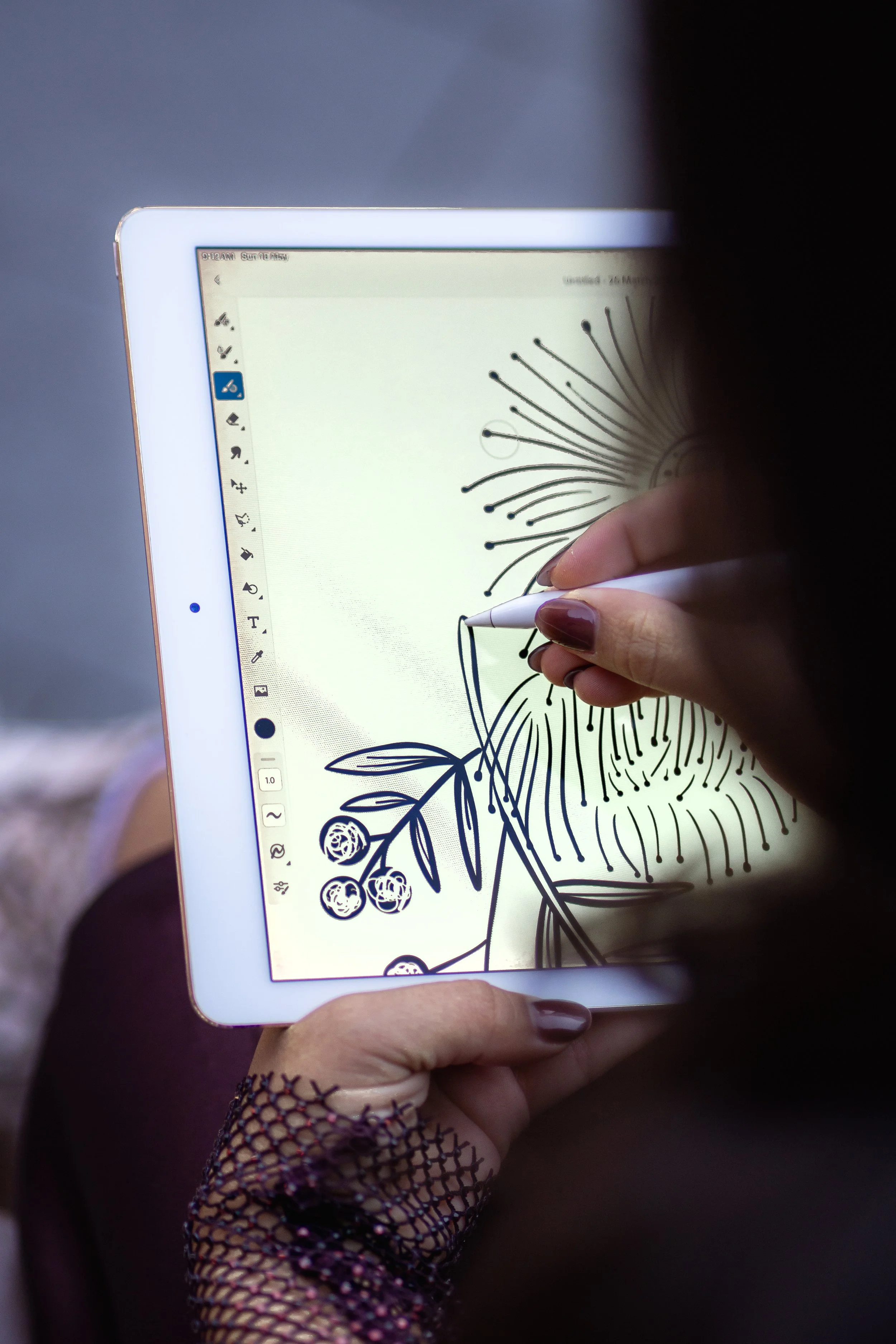 Person coloring a botanical illustration on a tablet using a stylus, with a finger covering part of the screen, and wearing a fishnet glove.