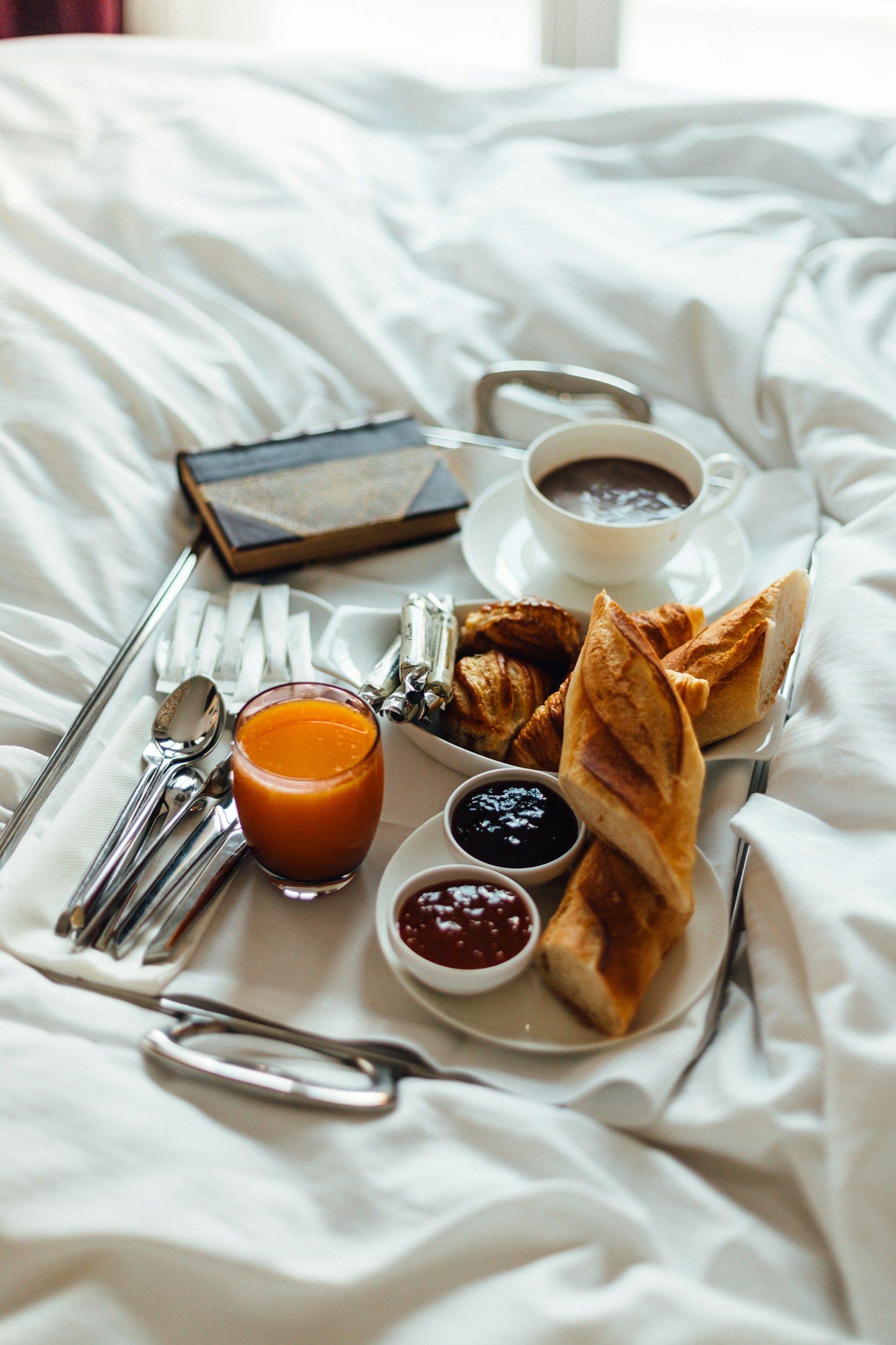 Breakfast in bed at a luxury hotel, with coffee, croissants, and fresh orange juice
