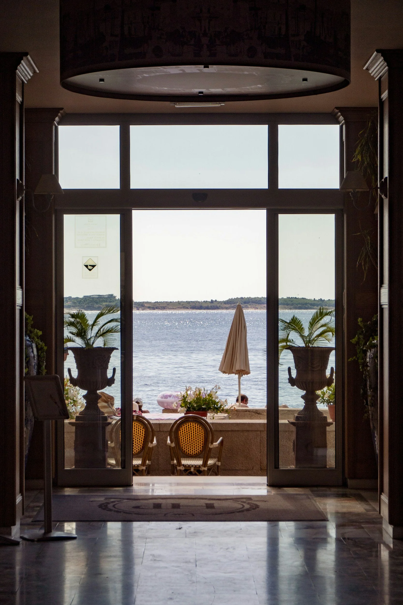 Elegant hotel hall overlooking the sea, with glass doors opening onto a coastal terrace