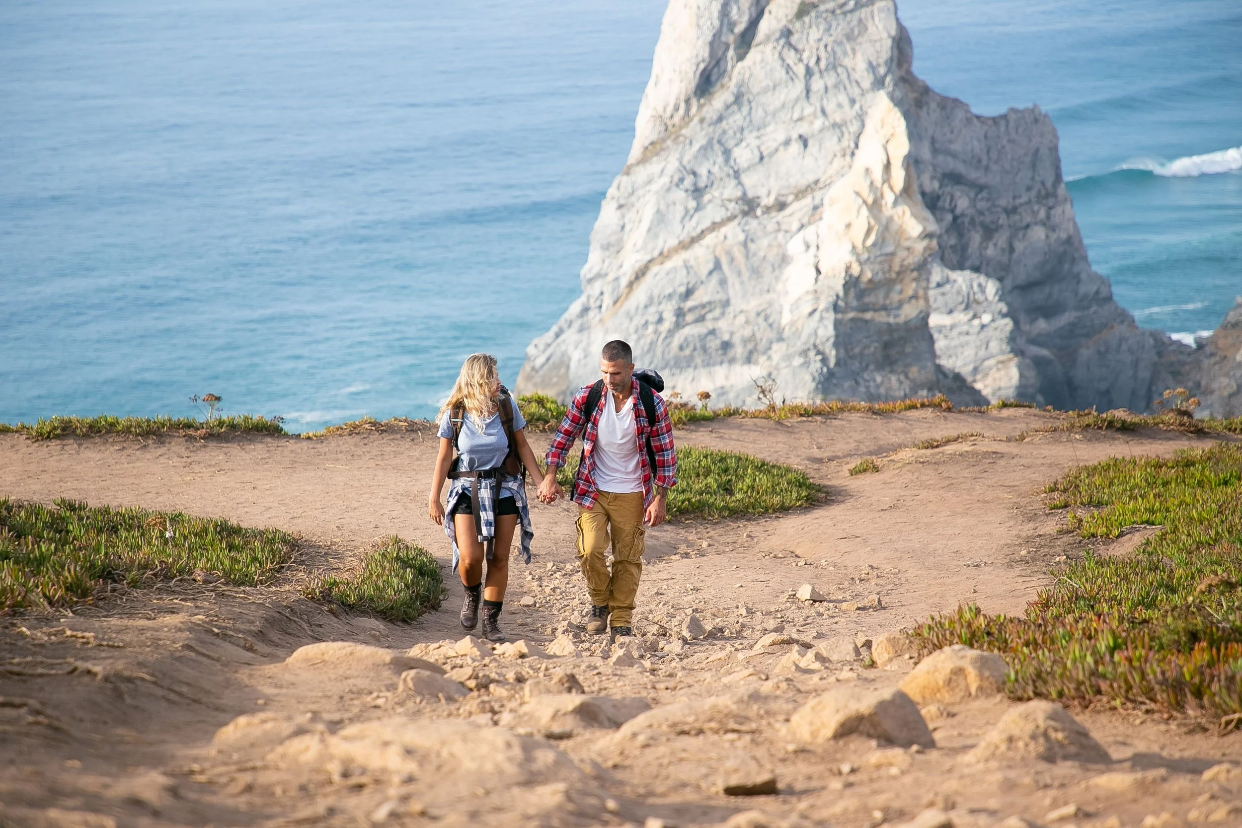 Couple hiking along the coast with dramatic cliffs and ocean views in Spain.