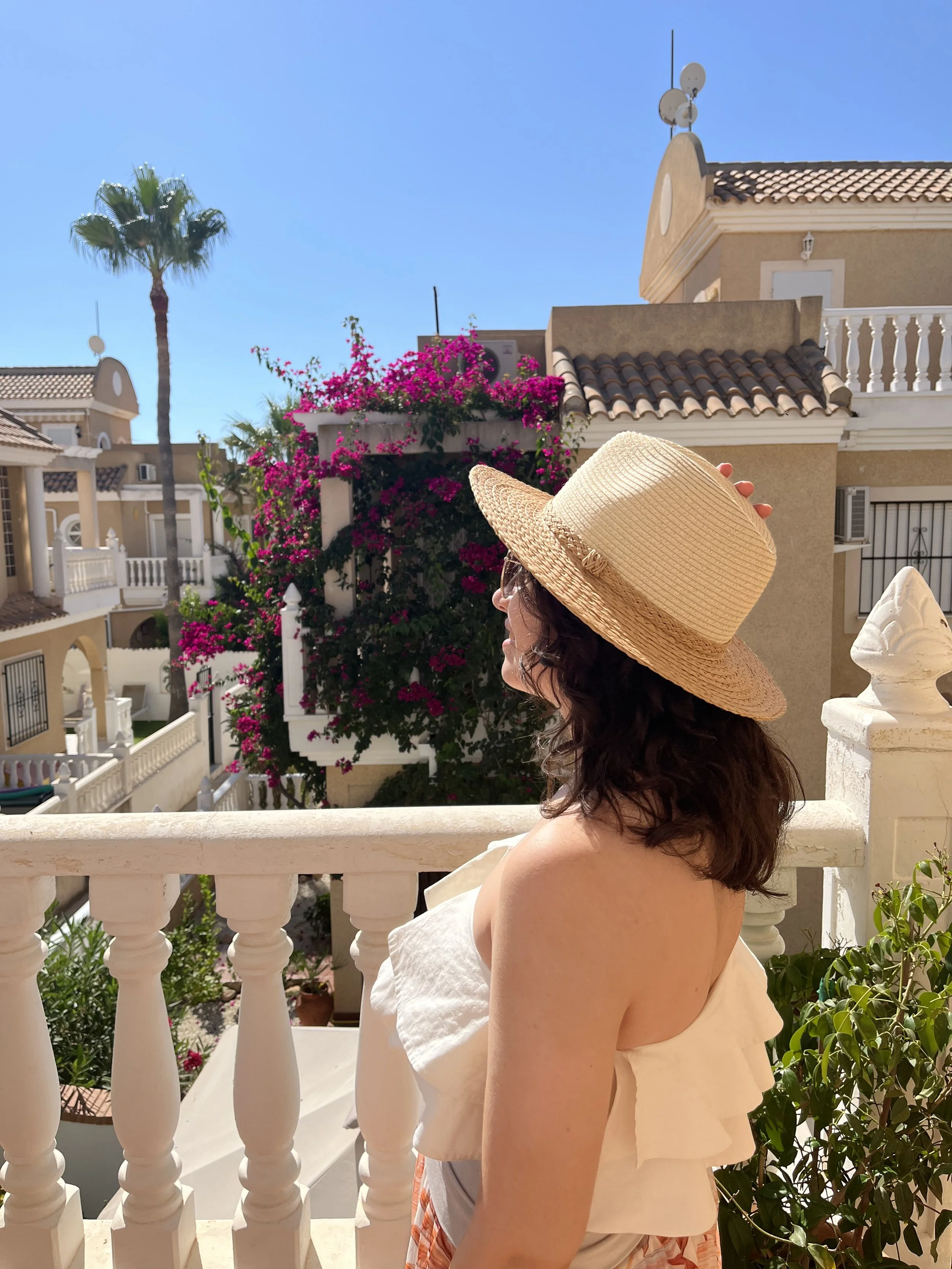 Travel planner standing on a balcony surrounded by bougainvillea in Spain