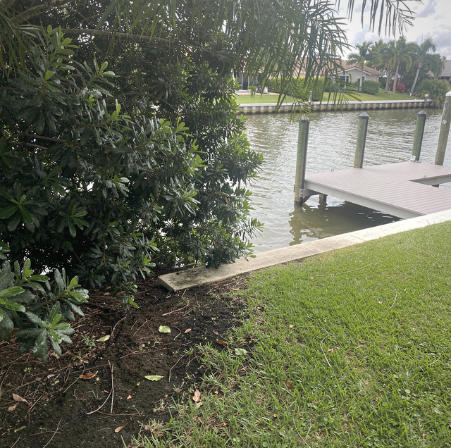 canal-front yard at dusk with dock and seawall