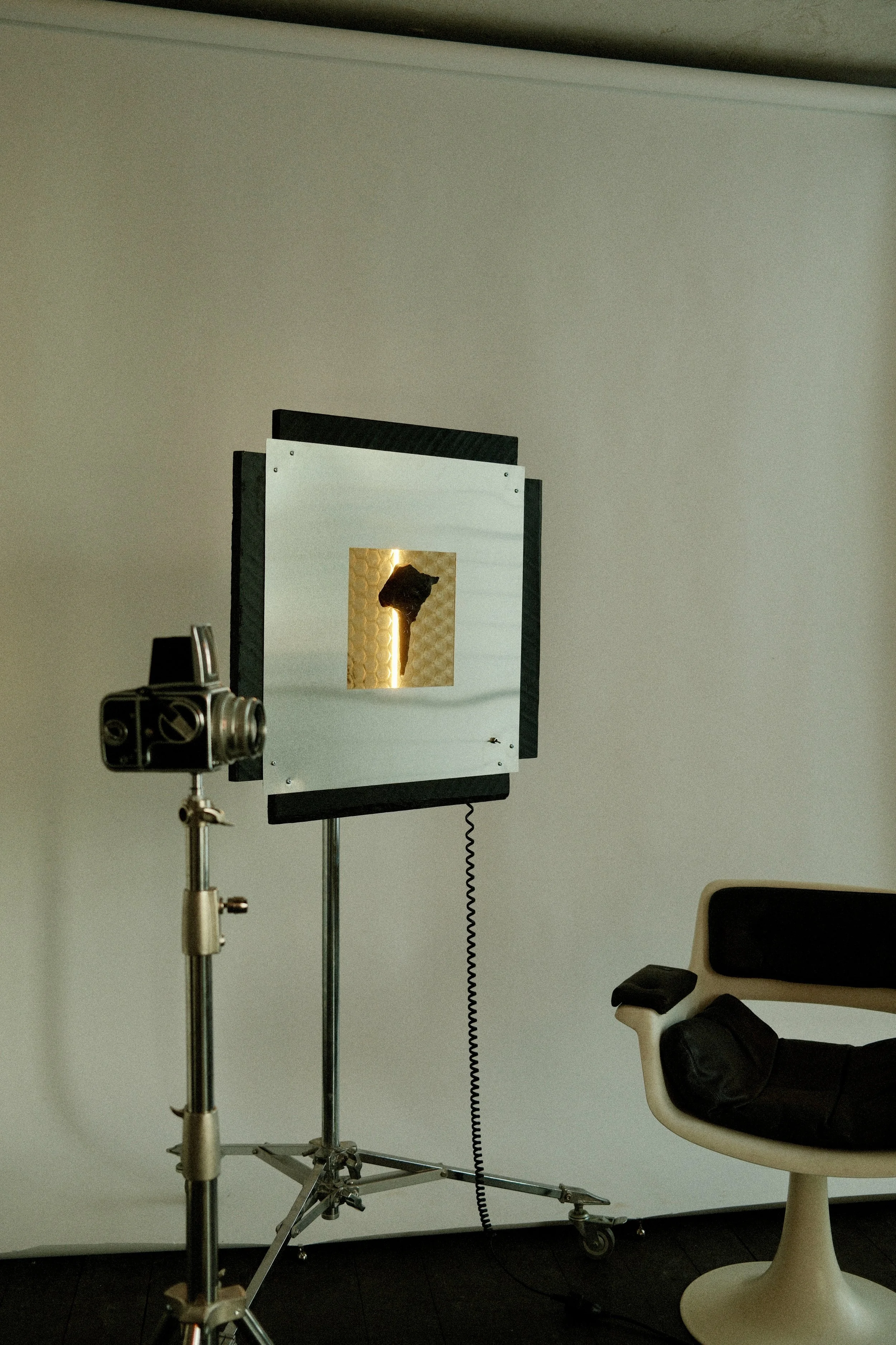 Et fotostudie setup med en refleksbox, lampe og en komfortabel stol i et studiemiljø.