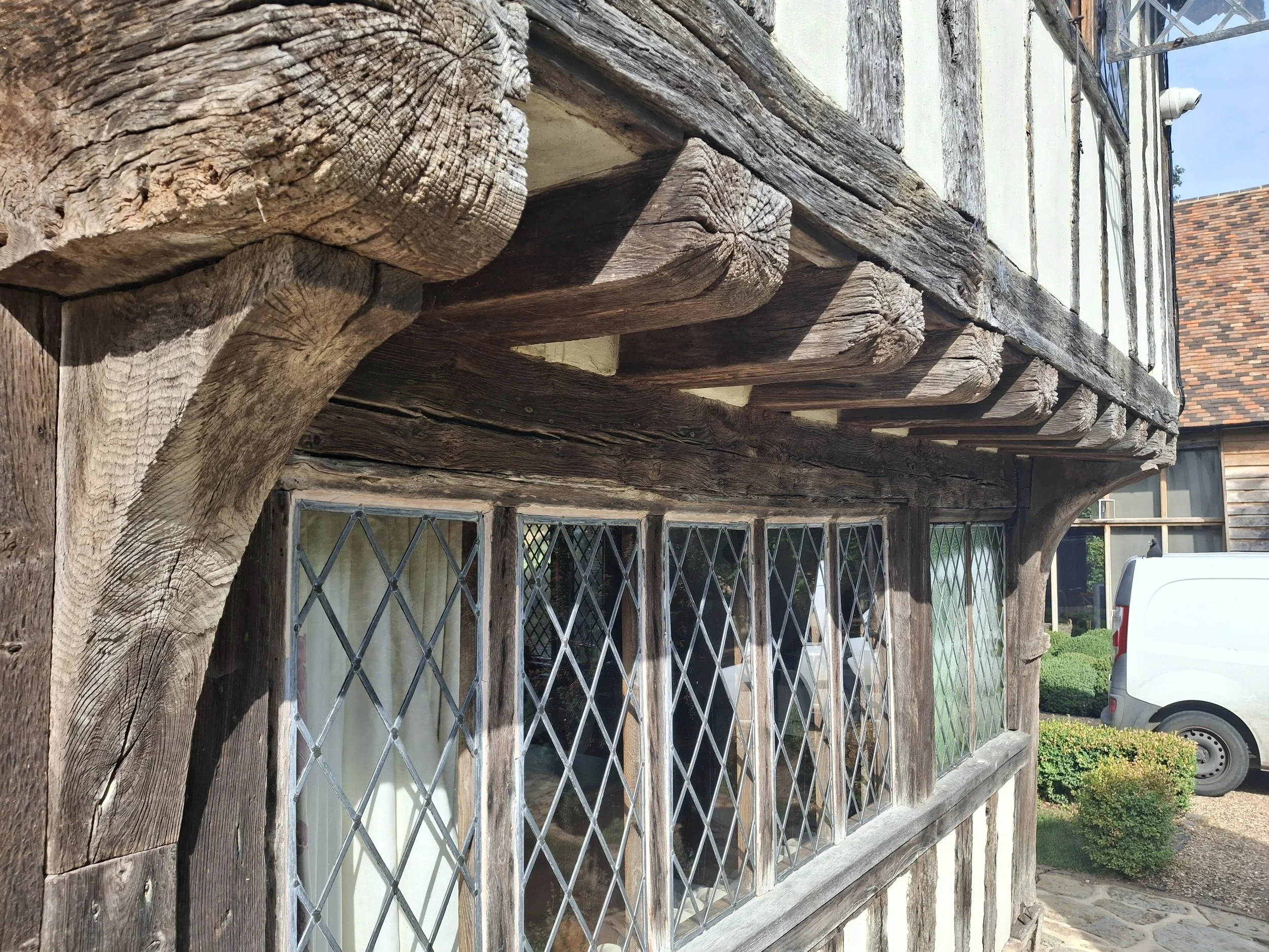 Close-up of weathered beams supporting a jetty and a diamond-patterned window. Part of a former Wealden Hall House.