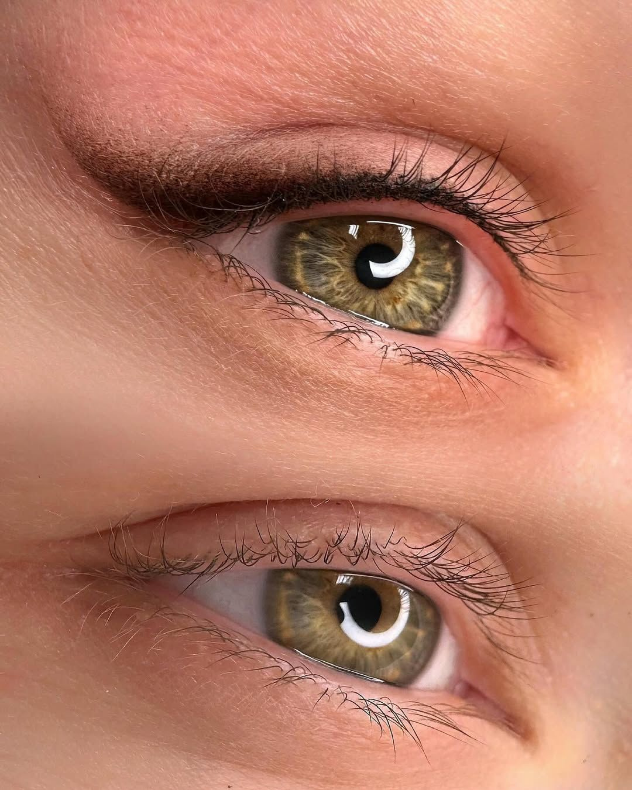 Nahaufnahme eines menschlichen Auges mit braunen Iris, auf der Oberfläche spiegeln sich Lichter.