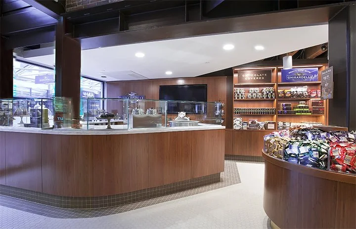 Chocolate and candy display counter in a store with shelves of assorted chocolates and snacks in the background.