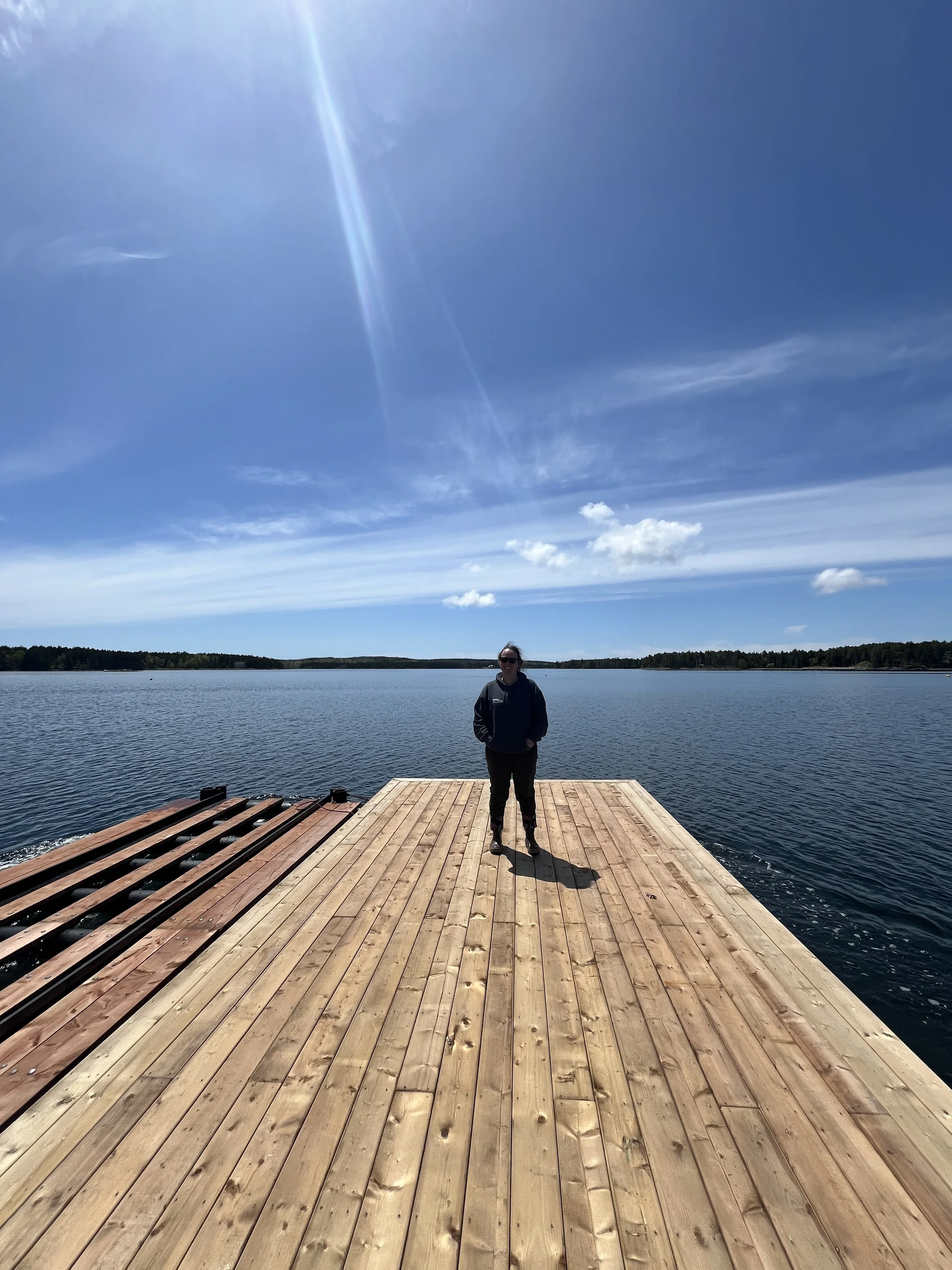 Laurie the owner standing at the end of a dock, showing off the new location of wild heart sea farm.