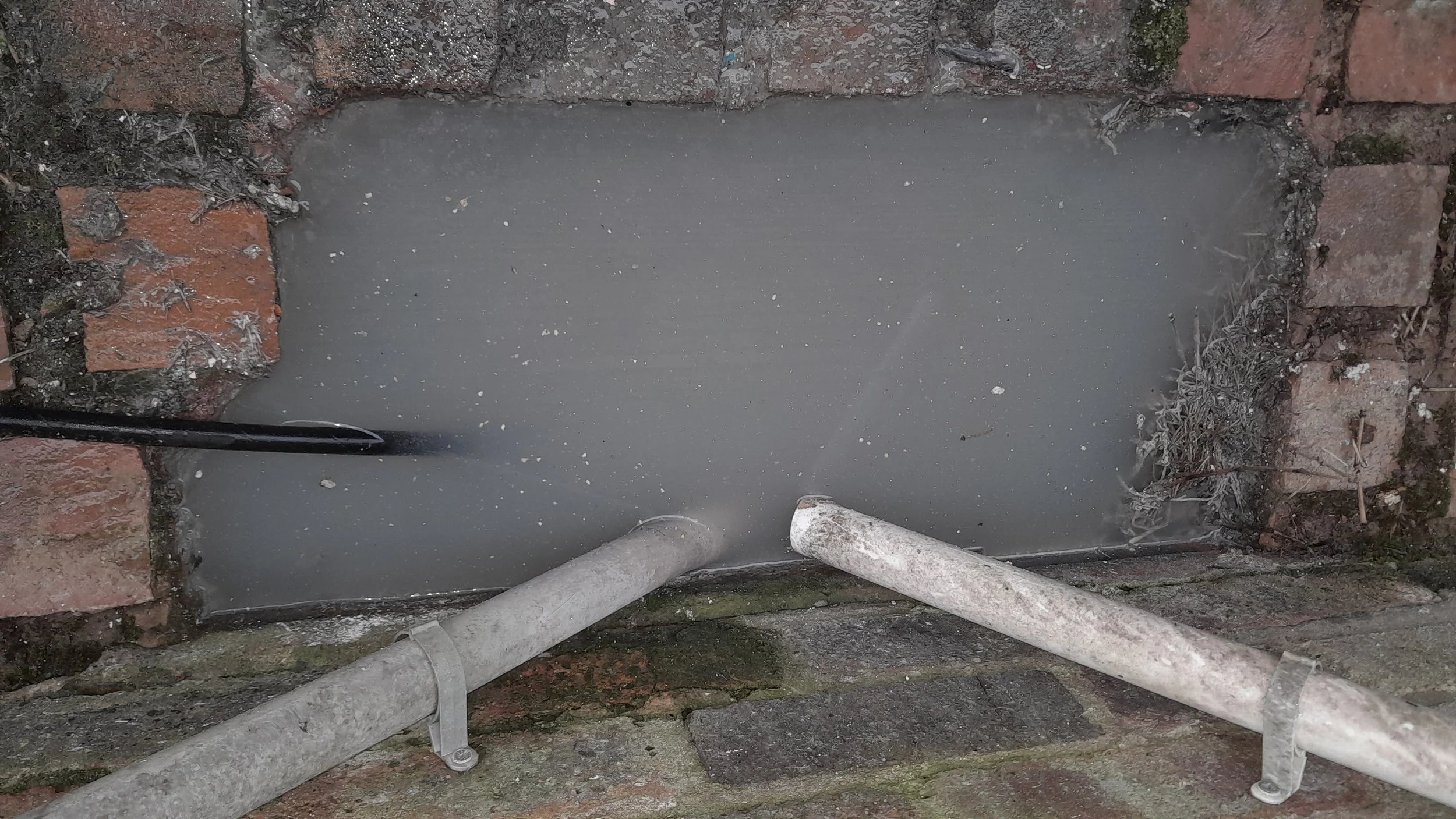 A blocked kitchen drain which is causing a smell is overflowing onto the patio.