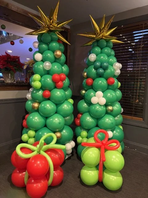 Two balloon Christmas trees decorated with green, white, red, gold, and silver balloons, topped with gold star balloons, for  a Christmas Party in Bucks County PA