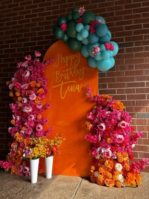 A 60th Birthday celebration with a flower arch and balloons.