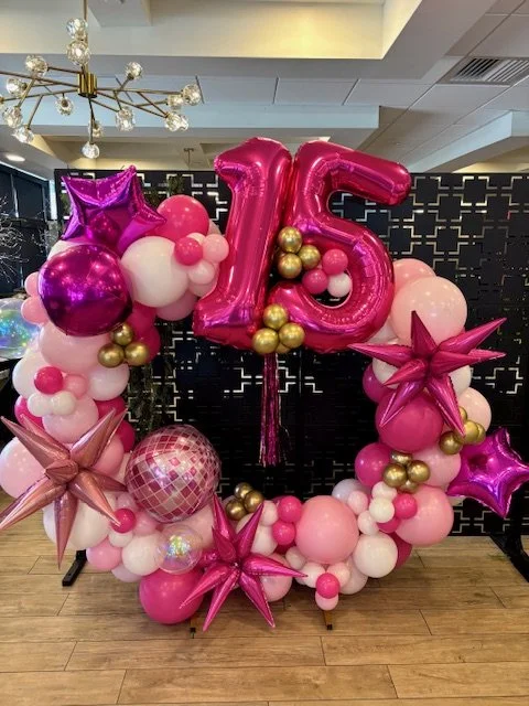 Balloon arrangement with number 15 and various pink, white, purple, gold, and disco-themed balloons, celebrating a 15th birthday.