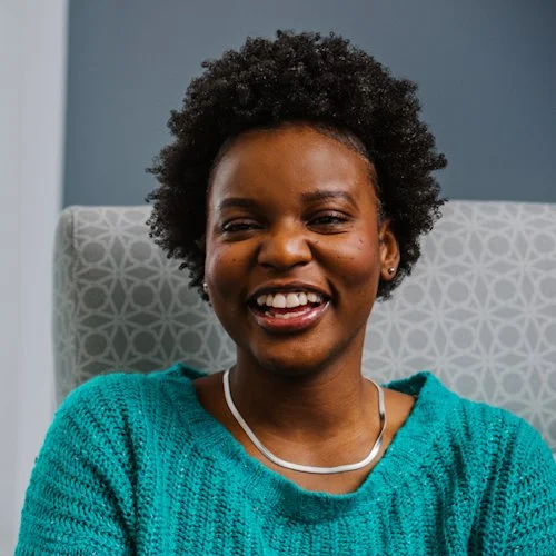 An image of a woman sitting in a chair and smiling.