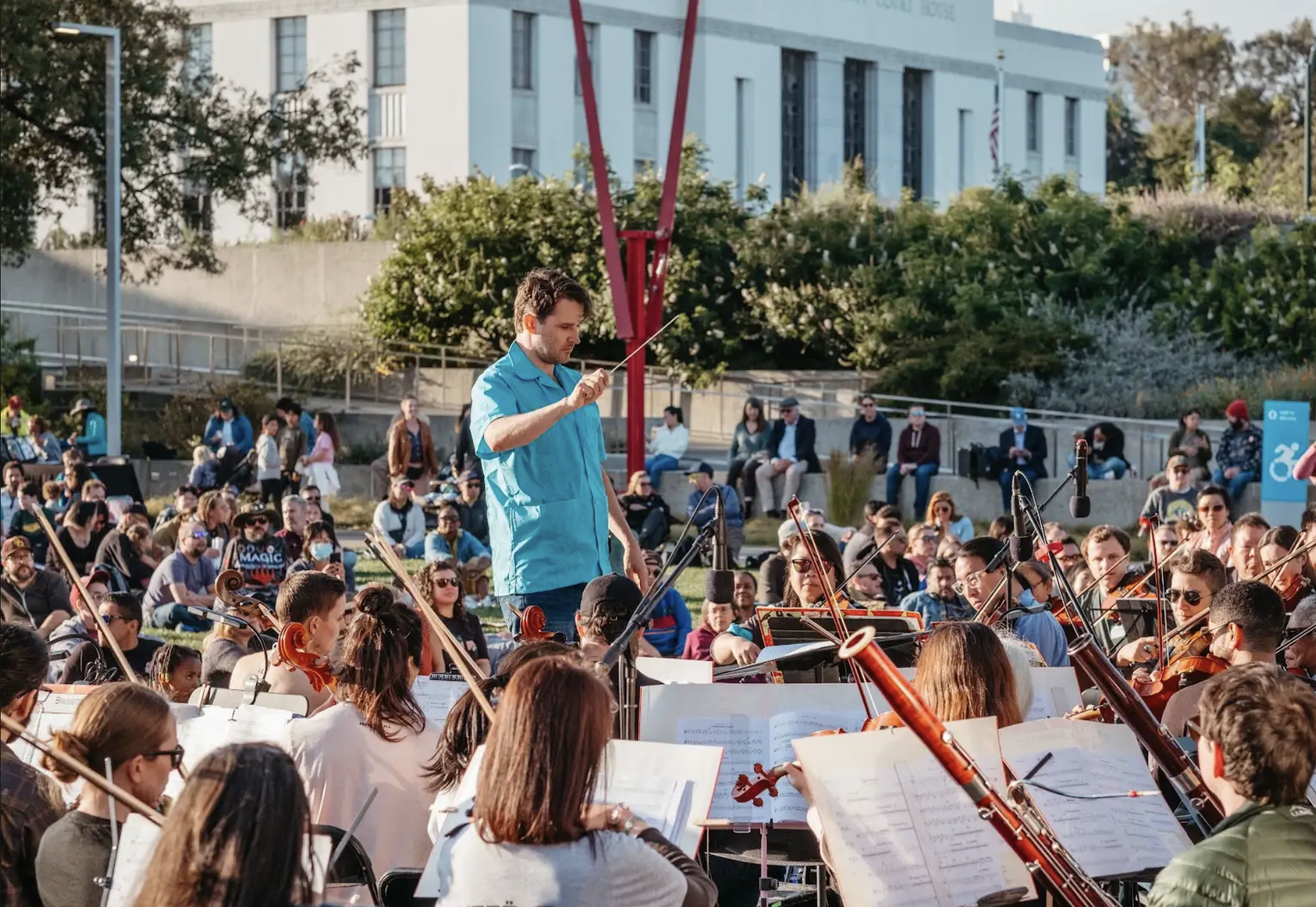 Conductor directing an orchestra in an outdoor setting at a community event