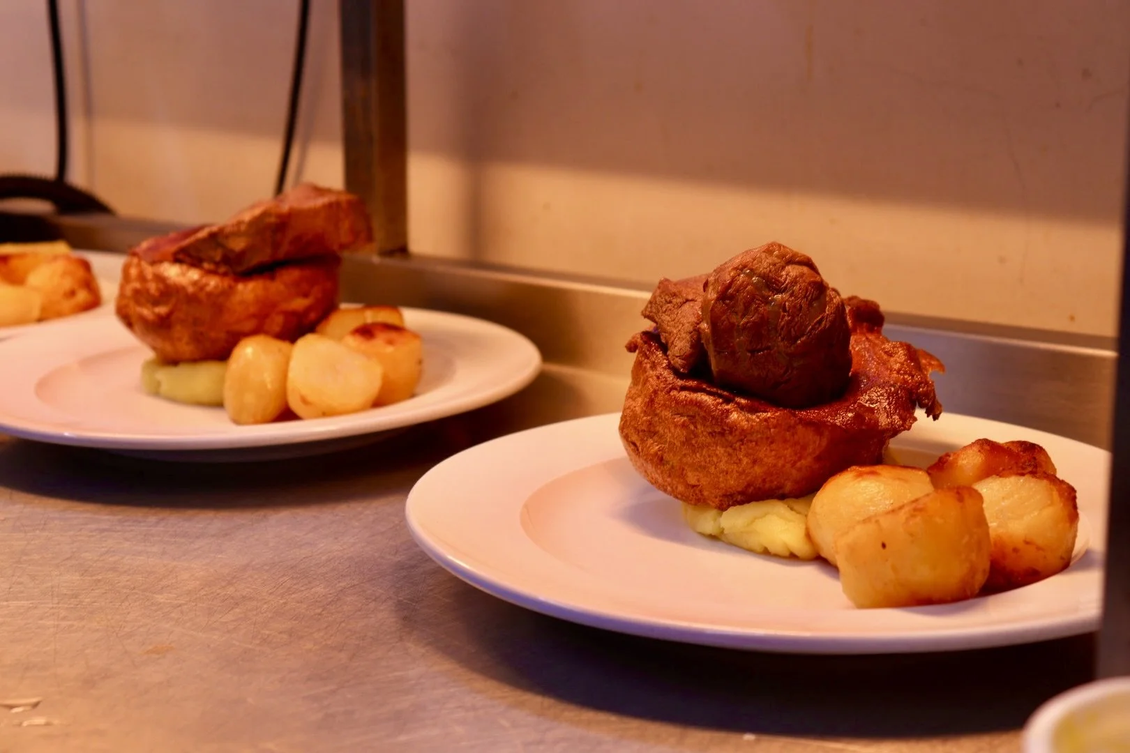 Two plates of Sunday roasts, on a kitchen countertop.