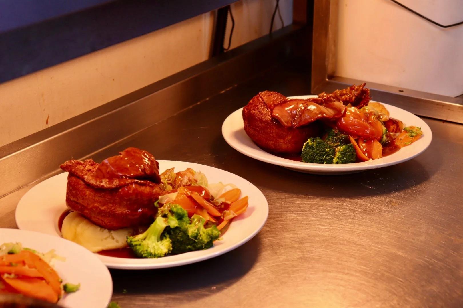Two plates of Sunday Roasts with gravy, mashed potatoes, broccoli, and mixed vegetables. One roast chicken, one roast beef.