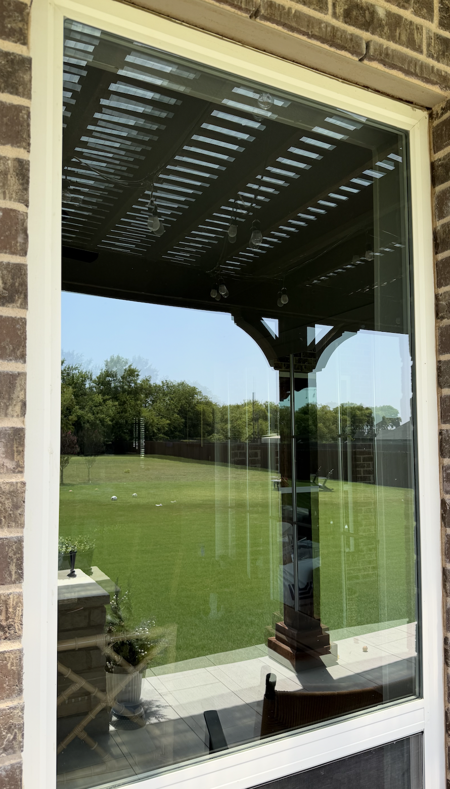 A standard window that measures 4ft by 6ft to that has been cleaned with cleaning solutions to show a clear view of the large backyard.