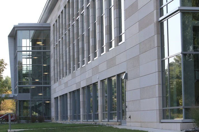 Side view of a modern office building with large glass windows and a glass staircase entrance.