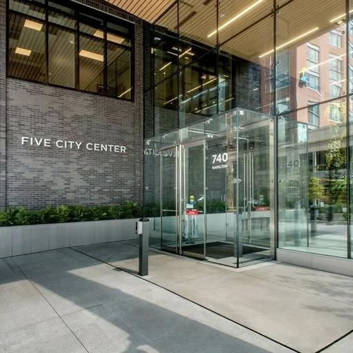 Exterior view of the Five City Center building with glass entrance, black brick facade, and the address 740 Hamilton, in an urban area.