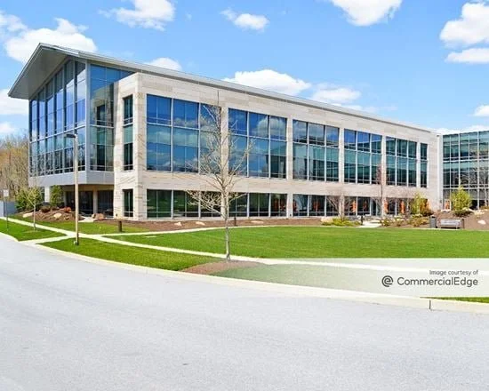 Modern office building with large glass windows and a landscaped lawn.