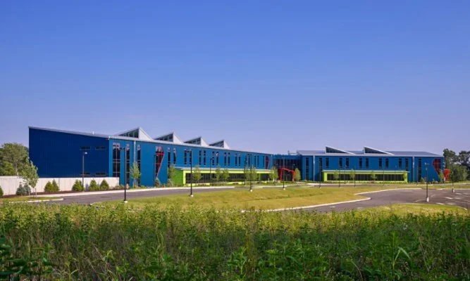 Modern blue school building with a green lawn and playground