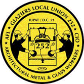 Circular yellow badge with black border and text. Center features two workers holding a steel beam marked '252' with tools, shield, and industrial elements. Text reads 'AFSCME GLAZIERS LOCAL UNION 252 - CIO - IUPAT / D.C. 21 - ARCHITECTURAL METAL & GLASS WORKERS'.