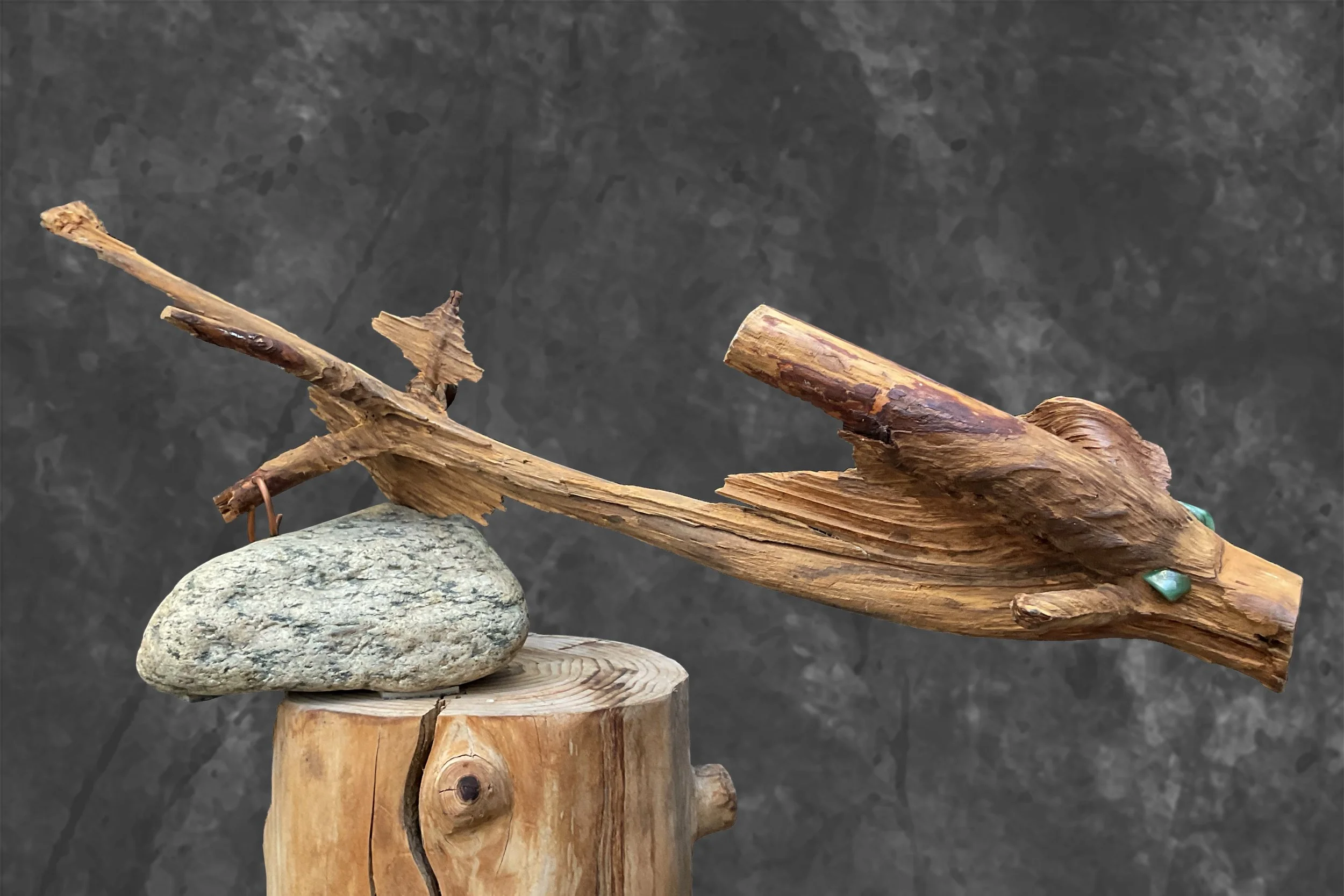 Steine, Holzstücke und getrocknetes Holz auf einem Podest gegen einen dunklen Hintergrund.