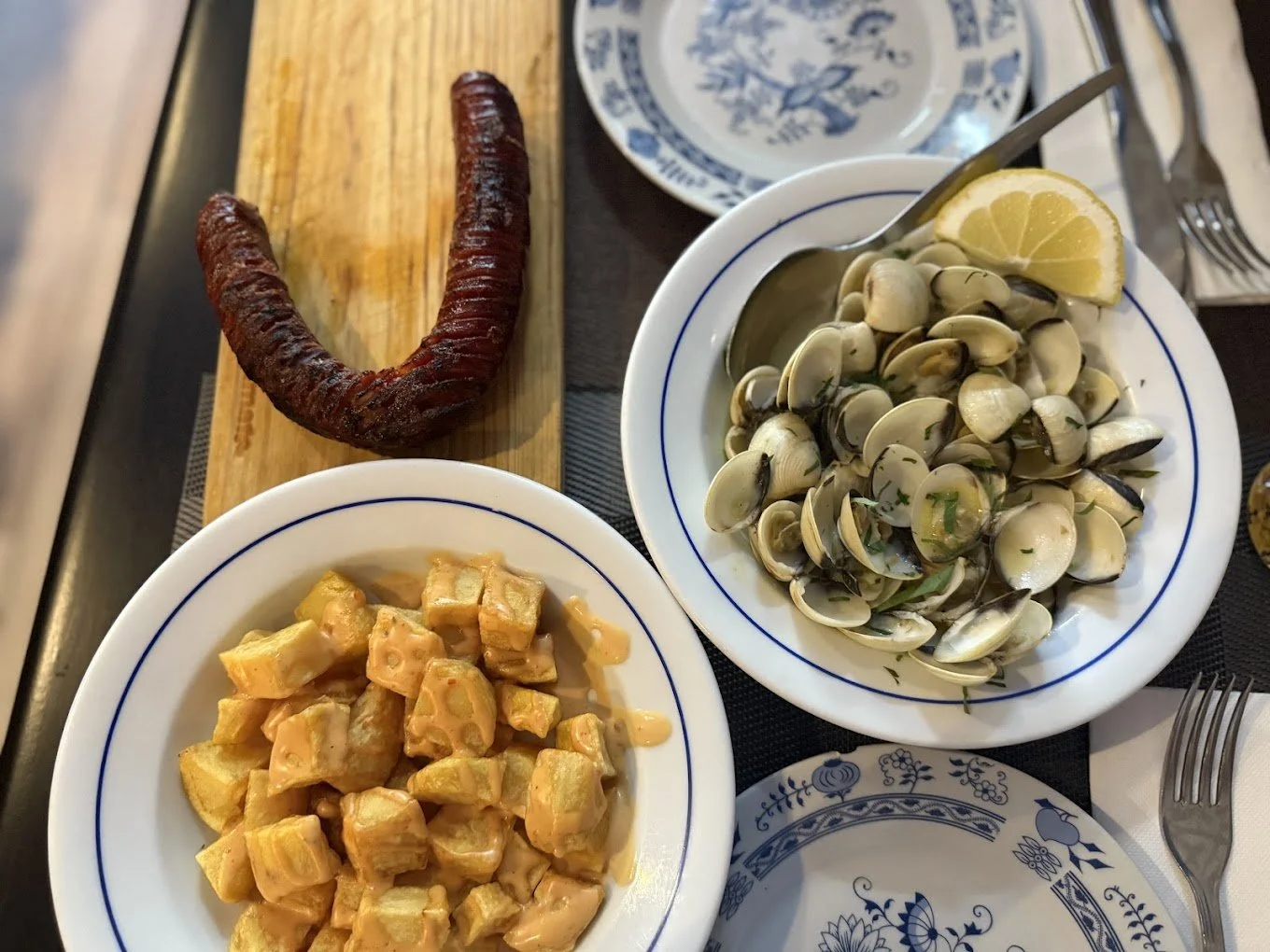 A meal with sausage, clam chowder with lemon, and macaroni and cheese.