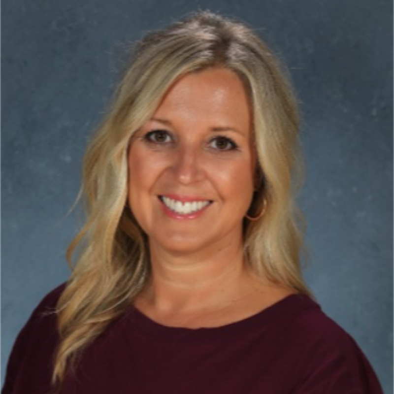 Dr. Rebecca Parks with blonde hair smiling, wearing a burgundy top, against a blue-gray background.