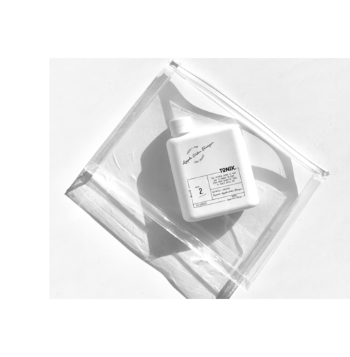 A white bottle of skincare or cosmetic product inside a clear plastic bag on a white surface