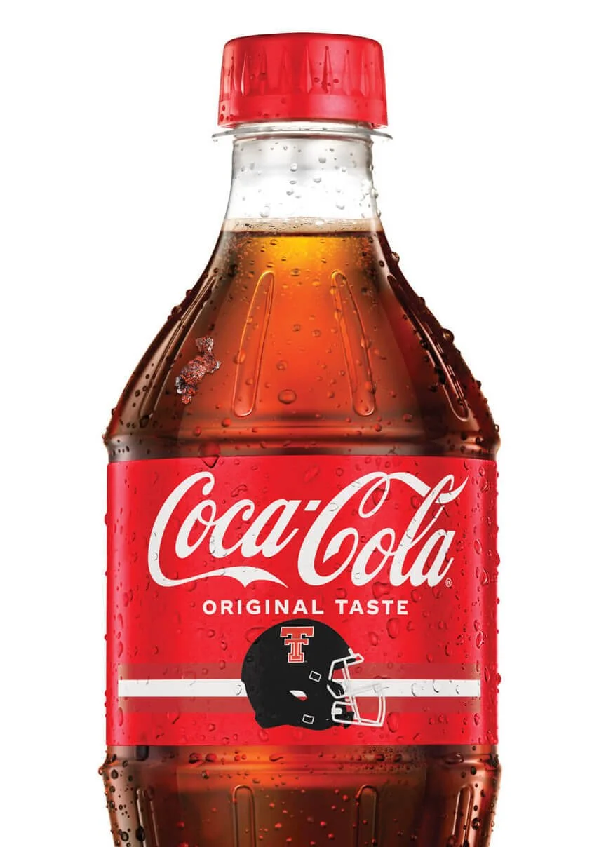A Coca-Cola bottle with a red cap and label, featuring a black and red football helmet logo.