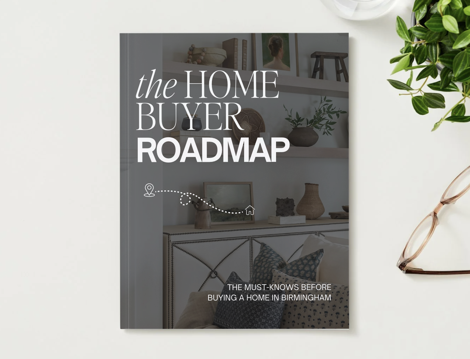 Cover of a guidebook titled 'The Home Buyer Roadmap: The Must-Knows Before Buying a Home in Birmingham' with a background image of a decorated interior space and a small icons of a location pin and a house connected by a dotted line.