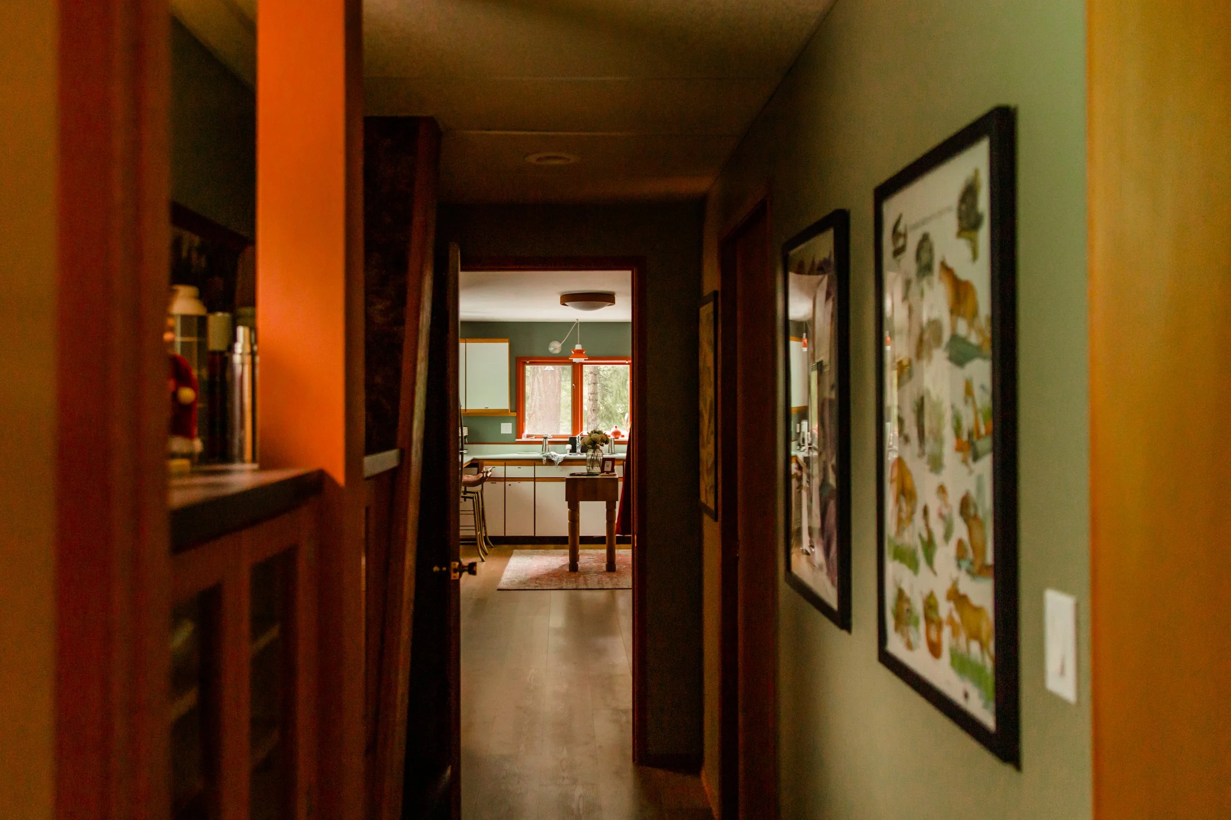 View through a hallway into a kitchen with a window, table, and chairs. Walls decorated with framed vintage Smokey The Bear posters.
