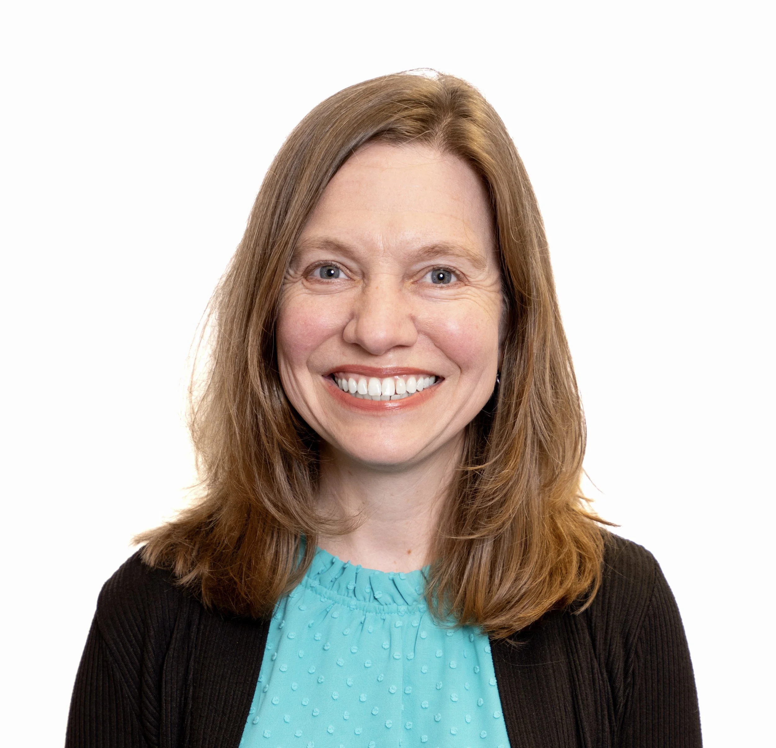 Close-up of a smiling woman with long, light brown hair, wearing a turquoise top and black cardigan, against a plain white background.
