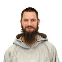 A man with a beard and long hair, wearing a light-colored hoodie, smiling at the camera.