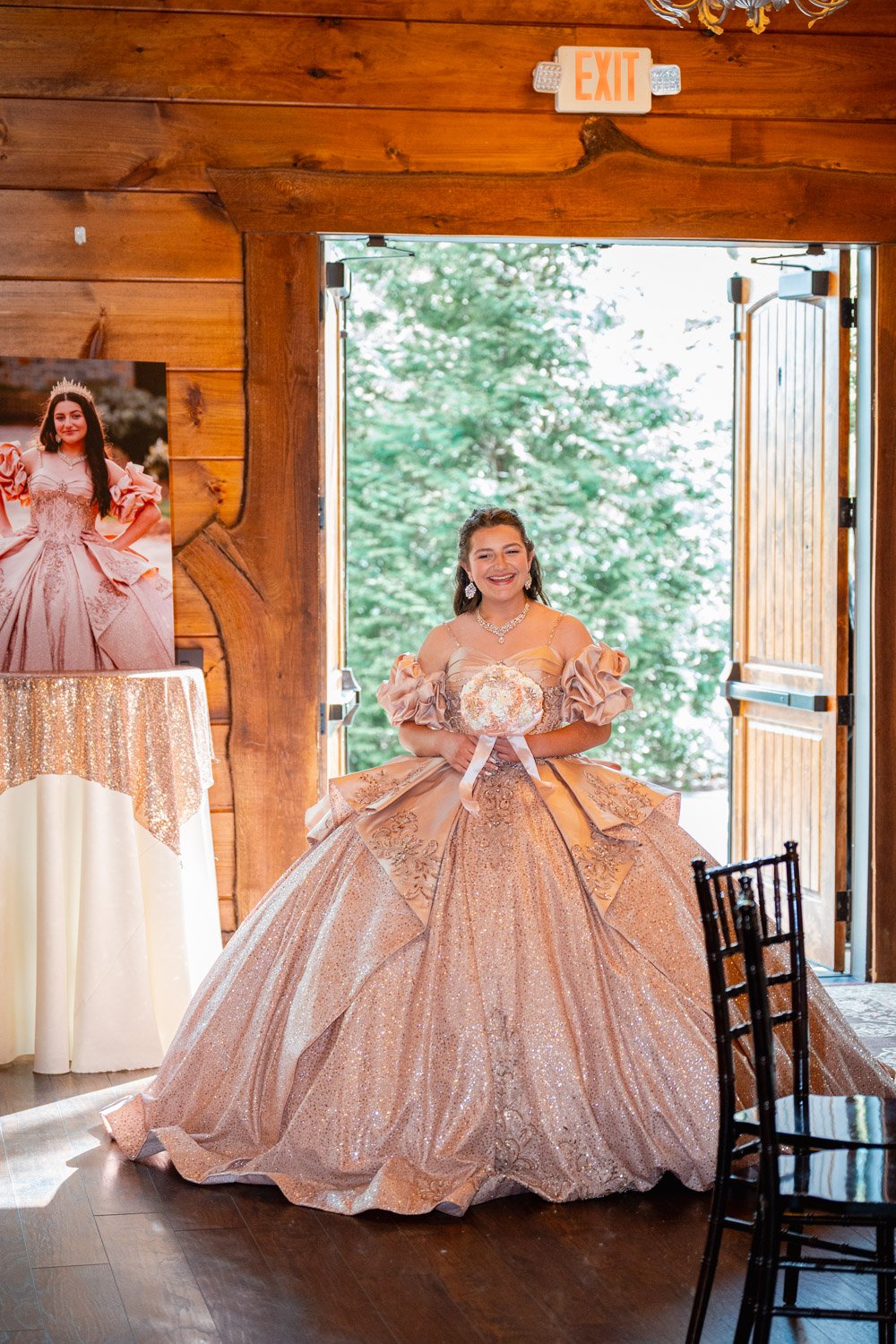 A young girl in an elegant peach ball gown with a full skirt, holding a bouquet, standing in a wooden doorway, smiling