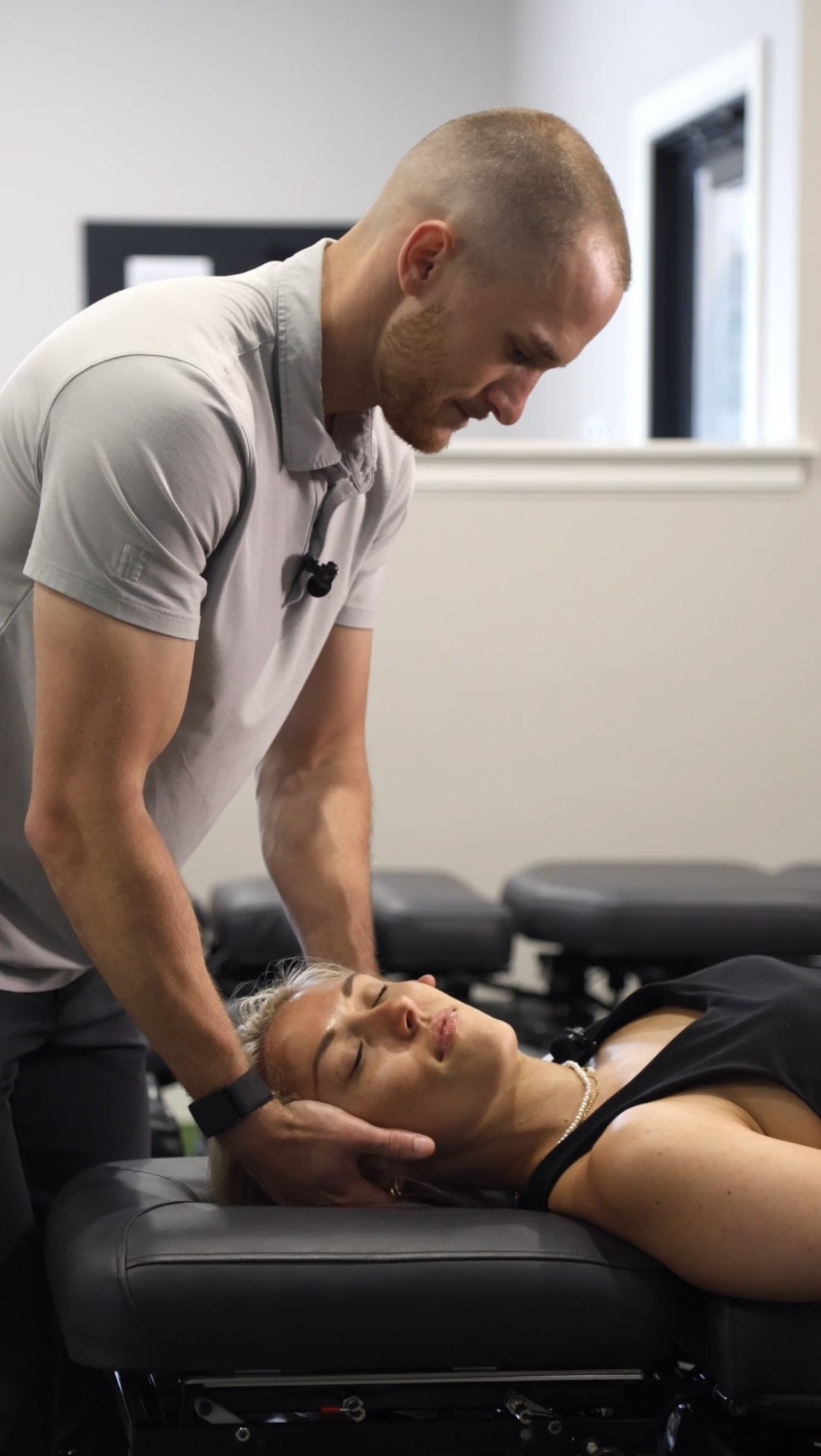 A man giving a chiropractic adjustment to a woman lying on a chiropractic table in a clinic.