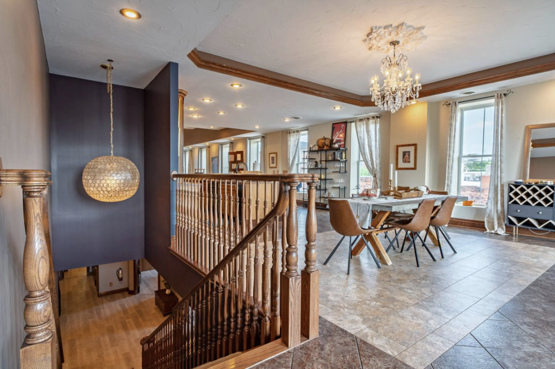 An open-concept living and dining area with large windows, a chandelier, wooden accents, and modern furnishings.