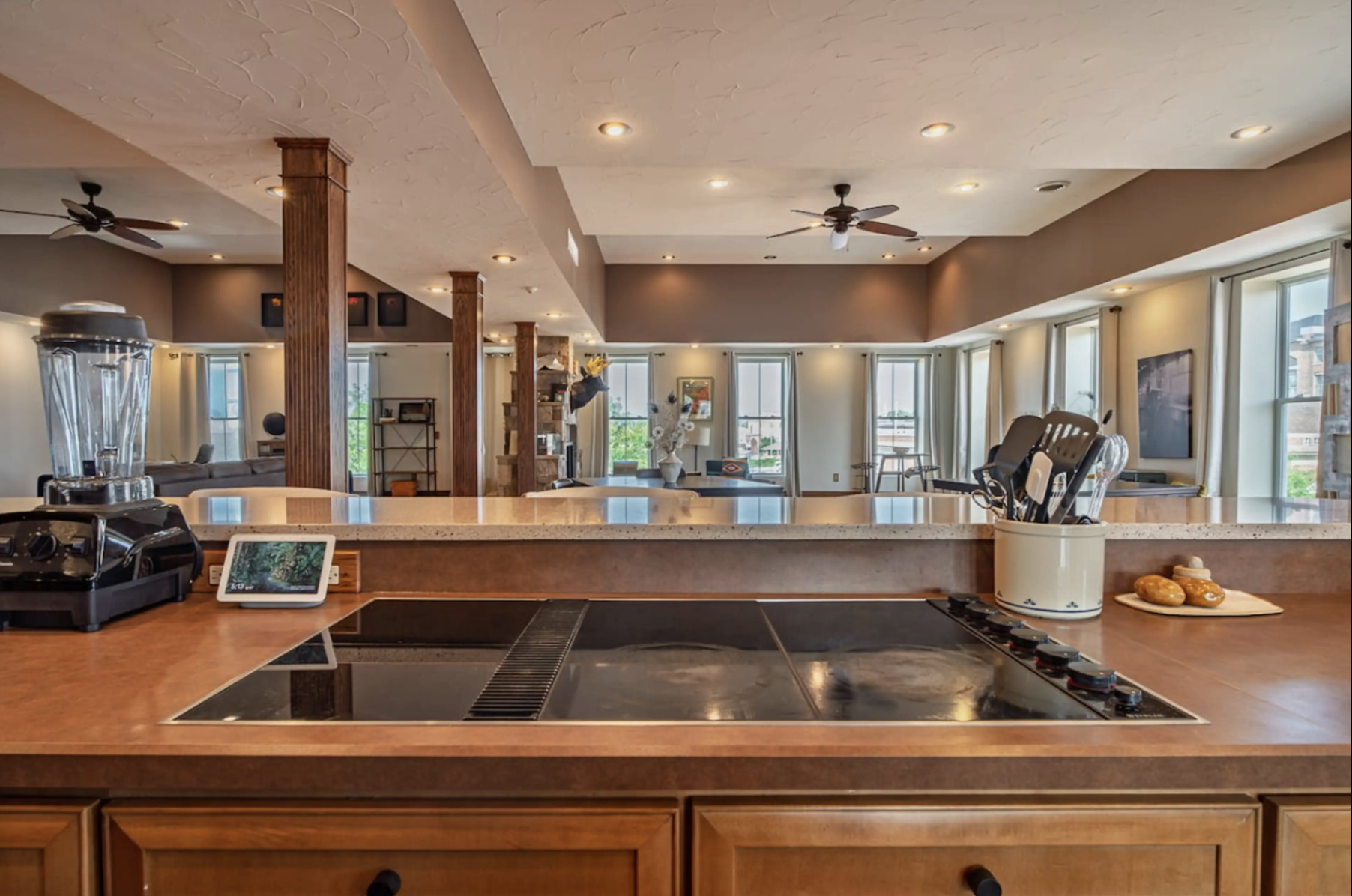 Open-concept kitchen with view of living room, multiple windows, ceiling fans, and various decorative items and furniture.