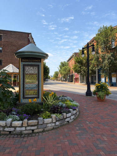 DeSales Corner red brick sides and red brick buildings, green trees lining the street and blue skies
