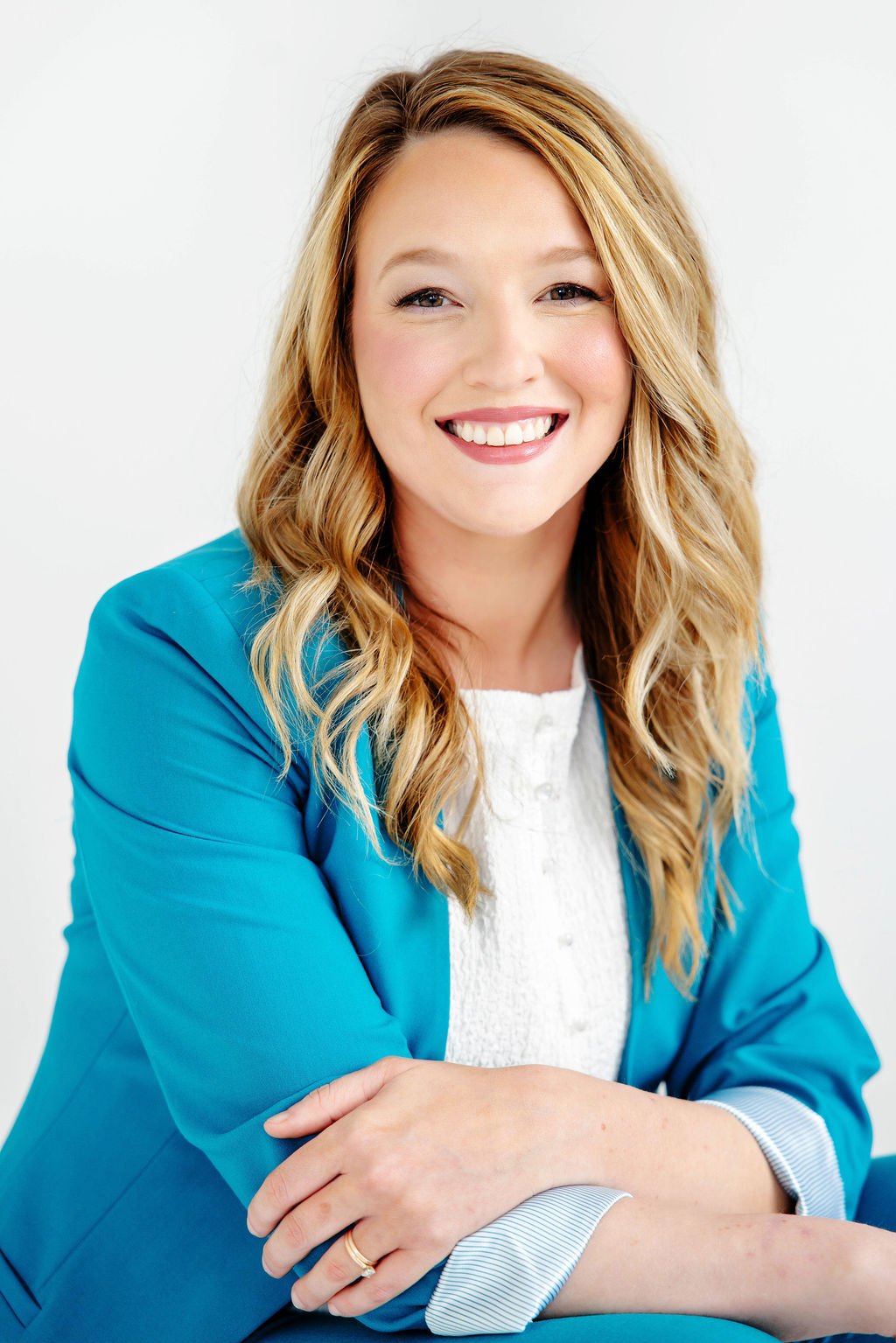 Taylor Dreigon, personal injury lawyer, smiling, wearing a blue blazer and a white top, sitting with arms crossed against a plain white background.