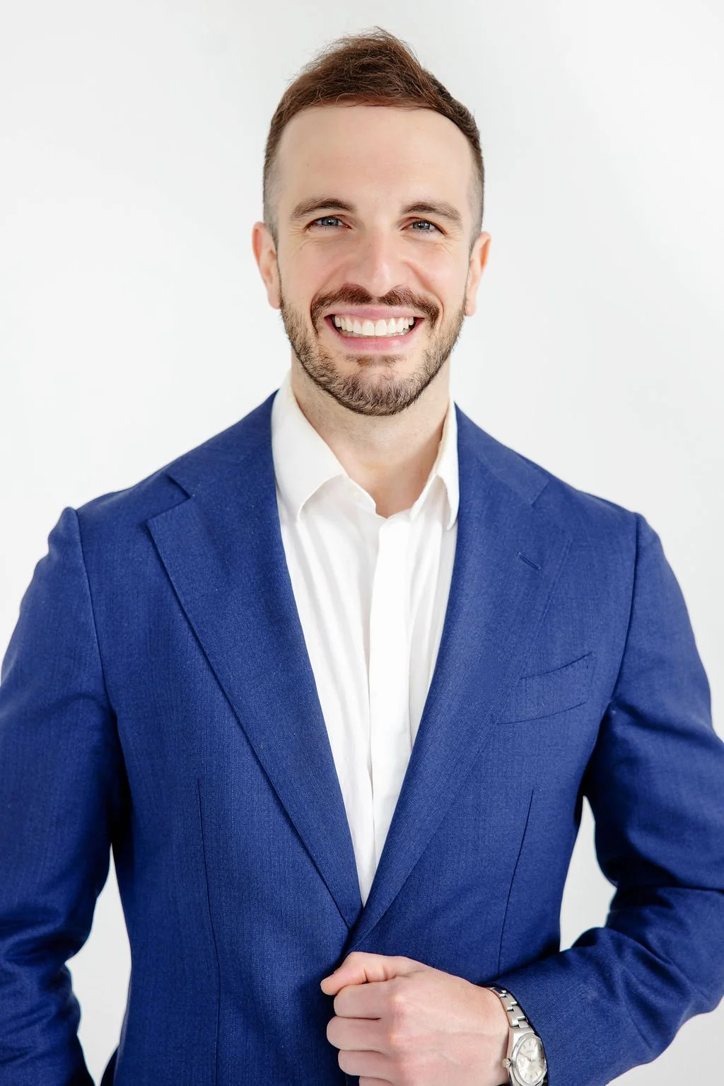 Austin Li Puma, personal injury attorney, smiling dressed in a blue suit and white shirt, standing against a plain white background.