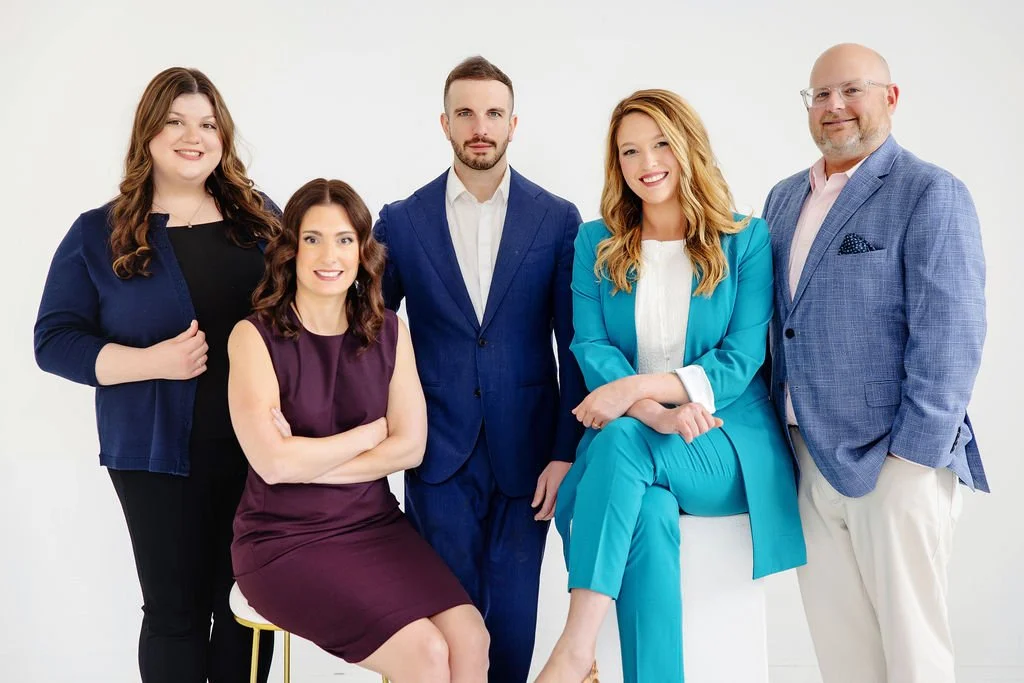 Group of five professionals from the De Villiers LiPuma team, three women and two men, posing together against a white background.