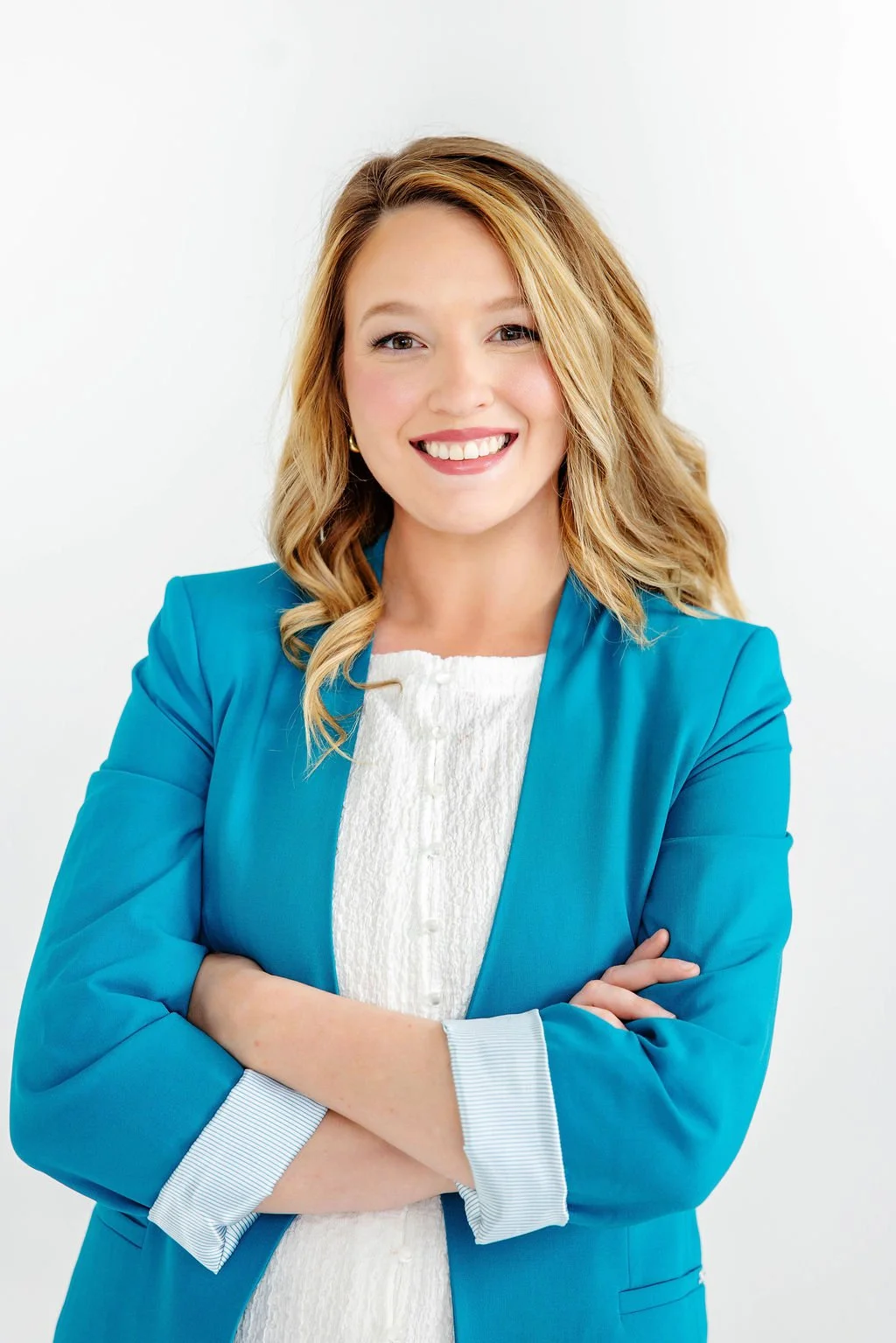 Taylor Dreigon smiling, wearing a blue blazer over a white blouse, standing against a plain white background.