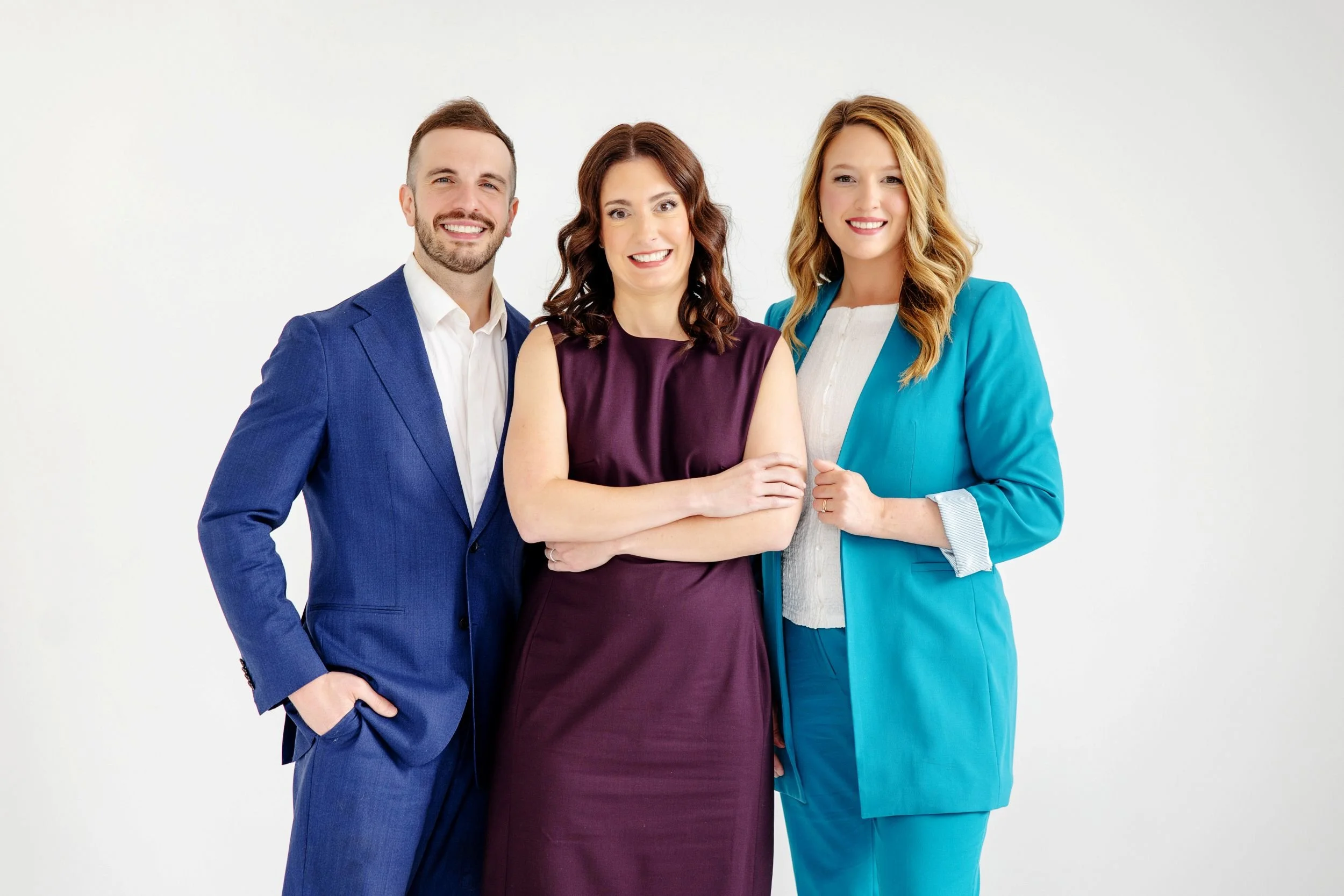Austin LiPuma, Alison De Villiers, and Taylor Dreigon standing together, smiling, and dressed in business attire, against a plain white background.