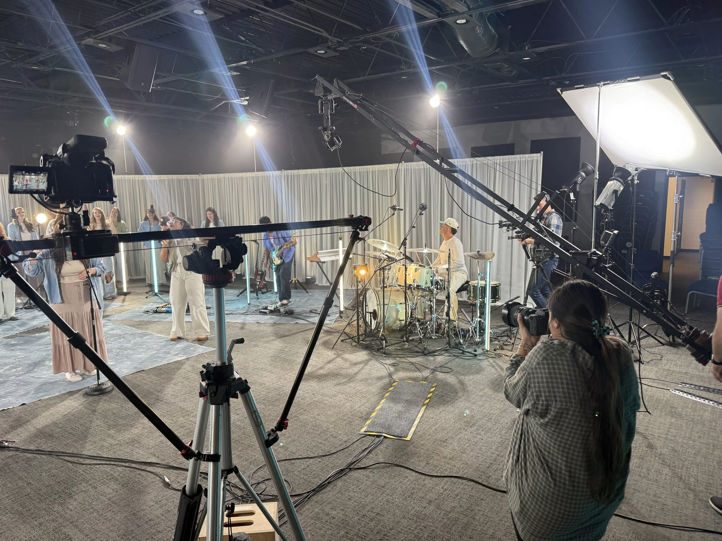 Film production set with lighting stands, camera support and a suspended soft light.