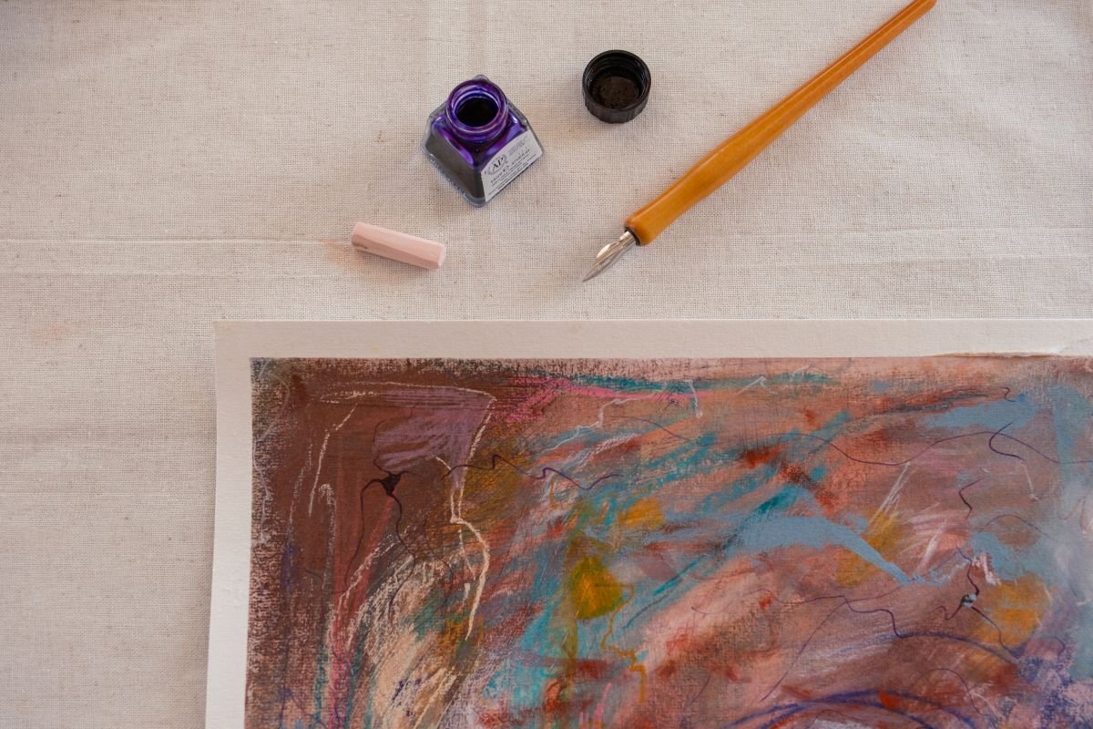 An array of ink, soft pastels, and ink pen arranged on a studio table for creative art therapy.