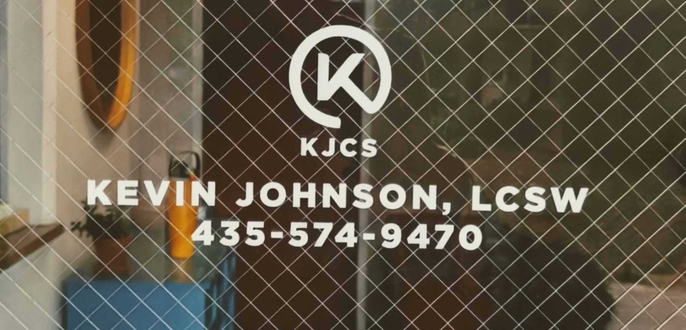 Business card for Kevin Johnson, LCSW, with contact phone number 435-574-9470, on a glass door with a diamond wire pattern.