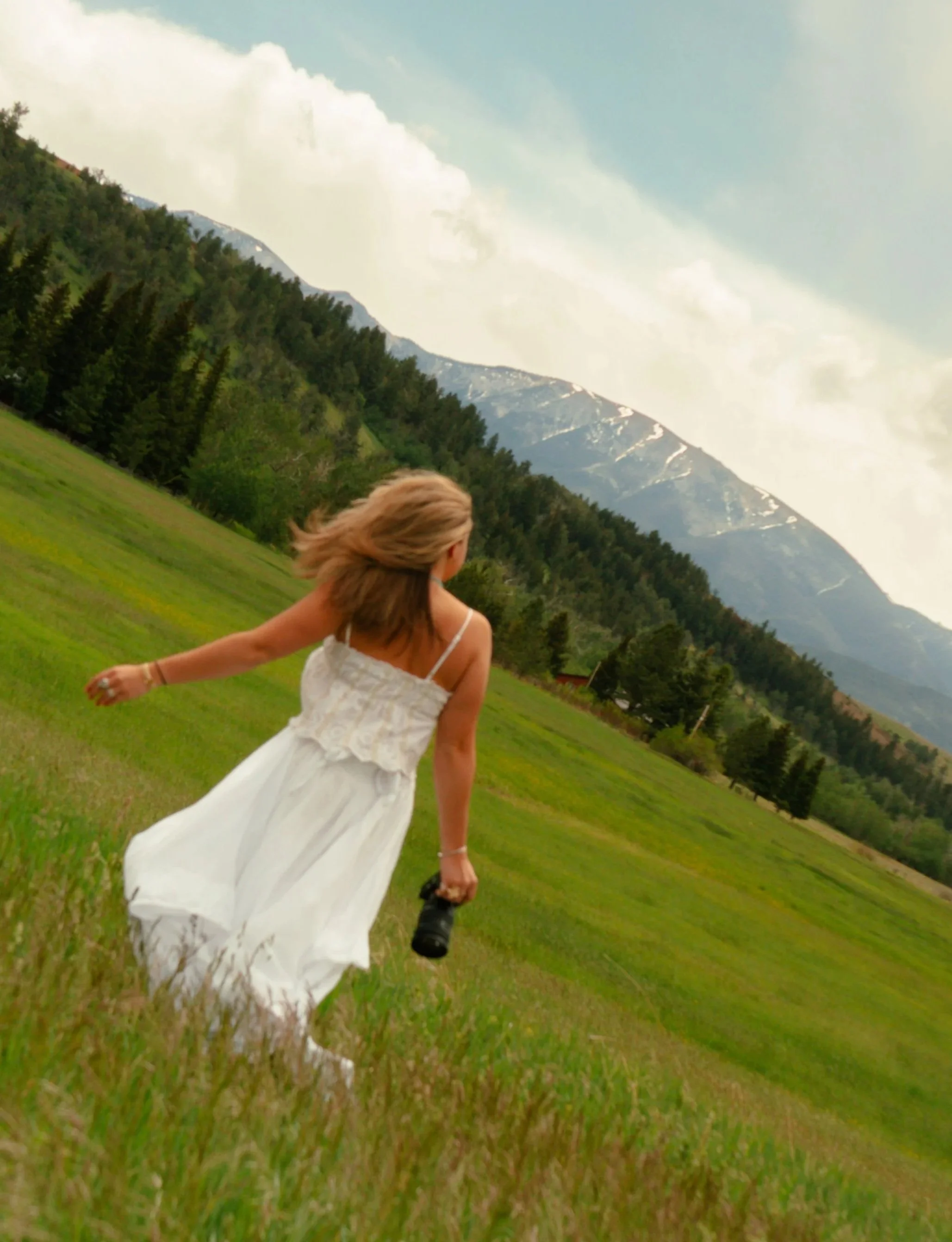 whimsical photography, girl in white dress running through a mountainous field, branding photography