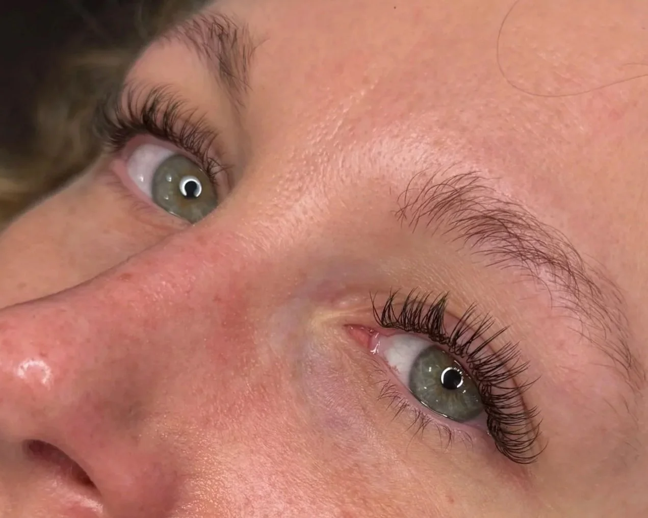 Close-up of two person's eyes, showing their eyelashes, eyebrows, and skin texture.