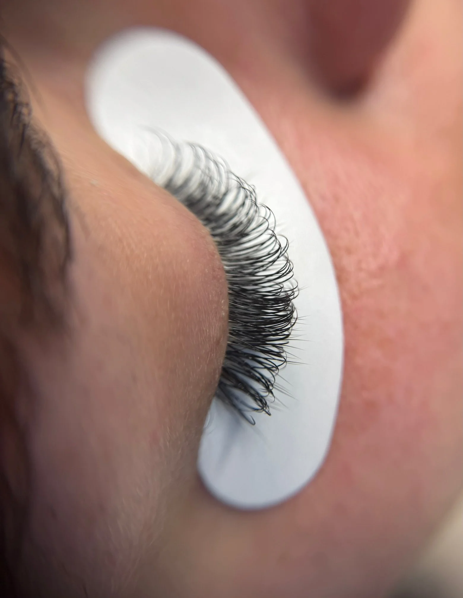Close-up of an eyelash extension on a person's eye, showing individual lashes attached to natural lashes.